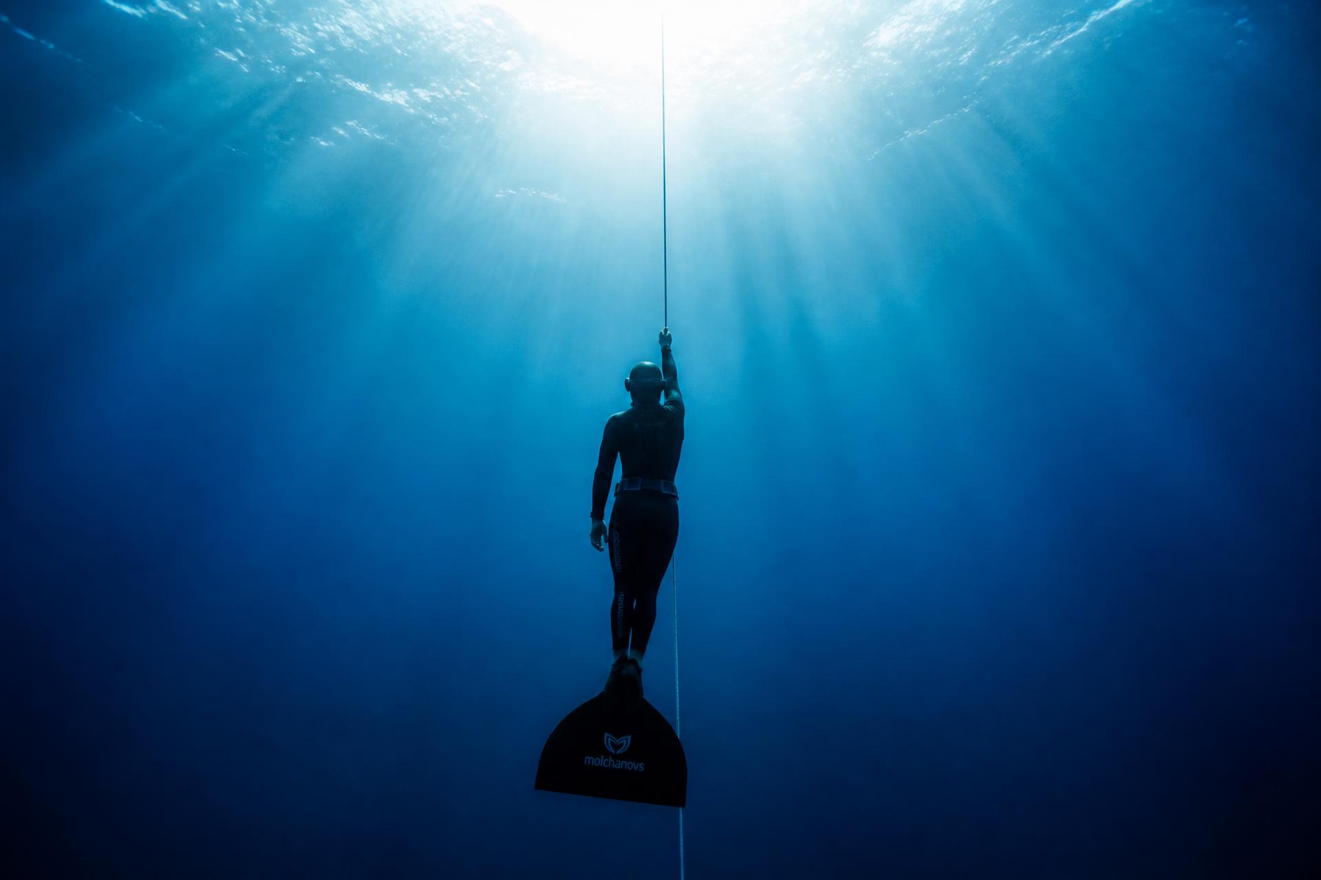 Freediver descending along a dive line in the deep blue Red Sea
